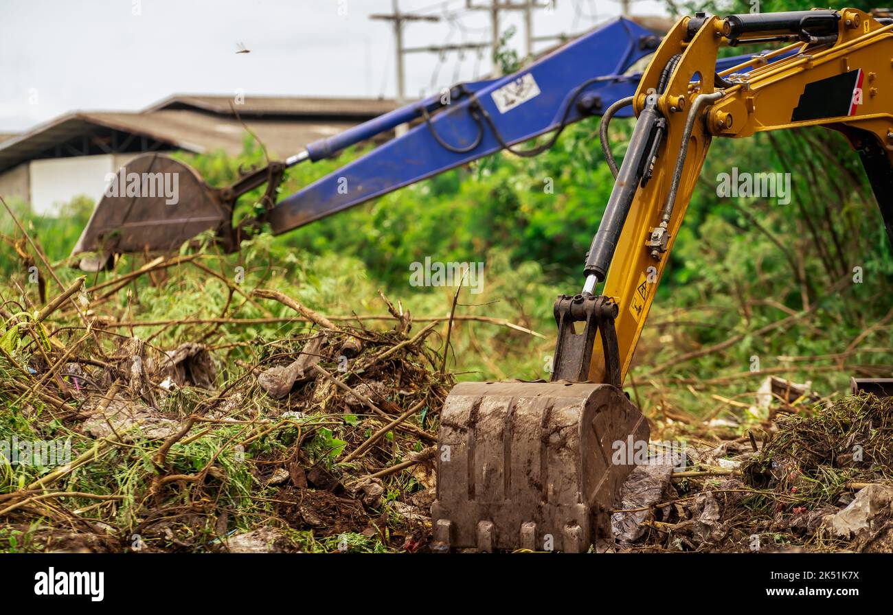 Retroescavatore che scava terreno in cantiere. Benna del retroescavatore che scava terreno. Compensazione ed estirpazione. Digger che lavora in cantiere. Messa a terra Foto Stock