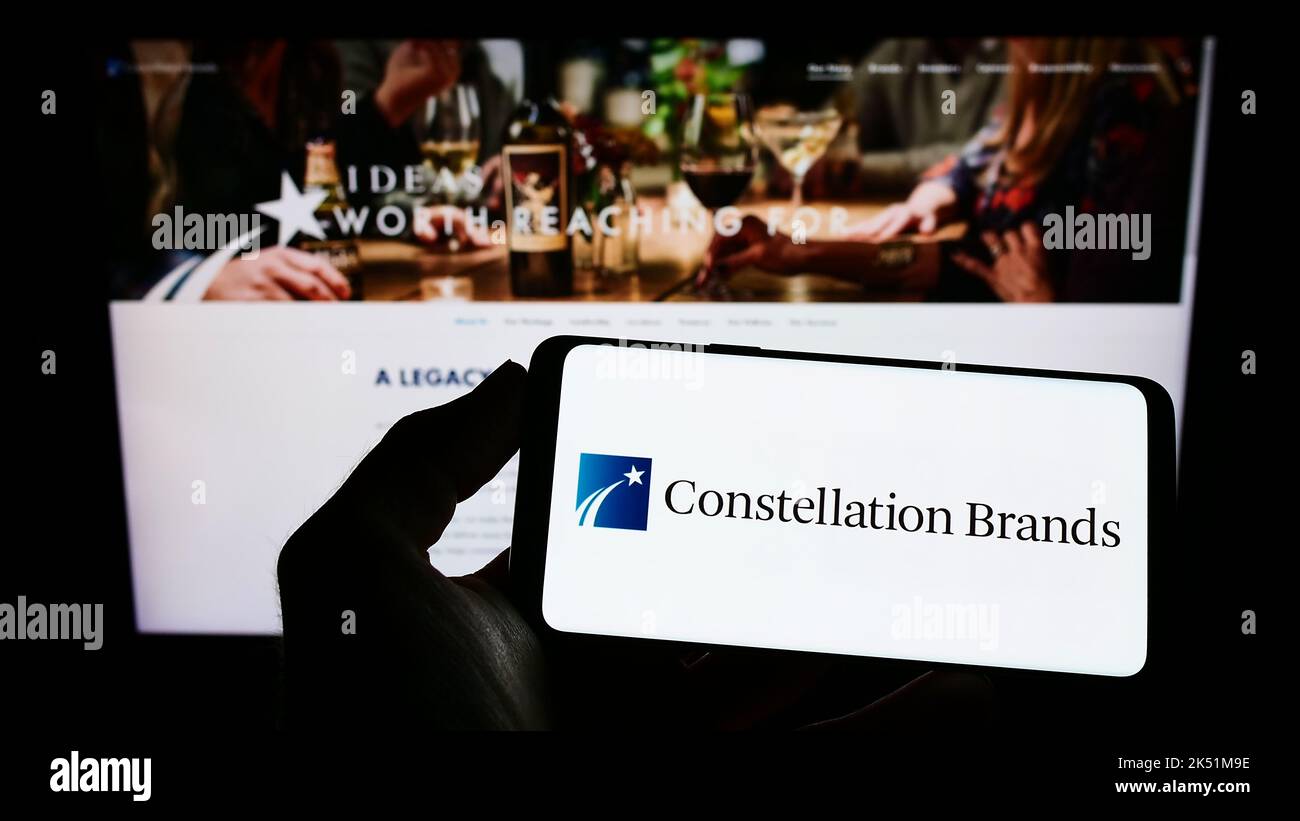 Persona che tiene il cellulare con il logo della società americana Constellation Brands Inc. Bevande sullo schermo di fronte alla pagina web. Messa a fuoco sul display del telefono. Foto Stock