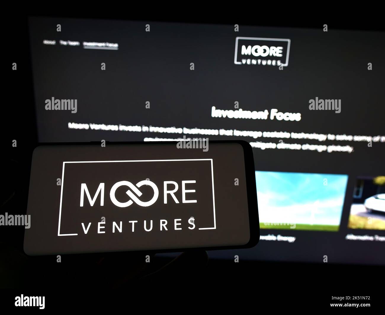 Persona che tiene il telefono mobile con il logo della società americana di investimento Moore Ventures sullo schermo di fronte alla pagina web. Messa a fuoco sul display del telefono. Foto Stock