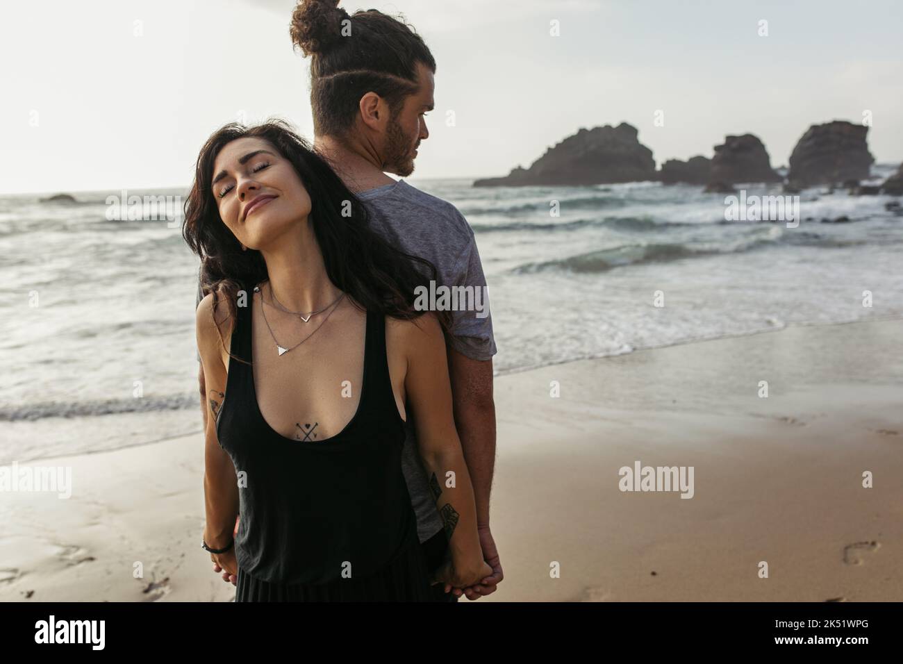 donna tatuata e uomo bearded in piedi indietro e tenendo le mani vicino oceano, immagine di riserva Foto Stock