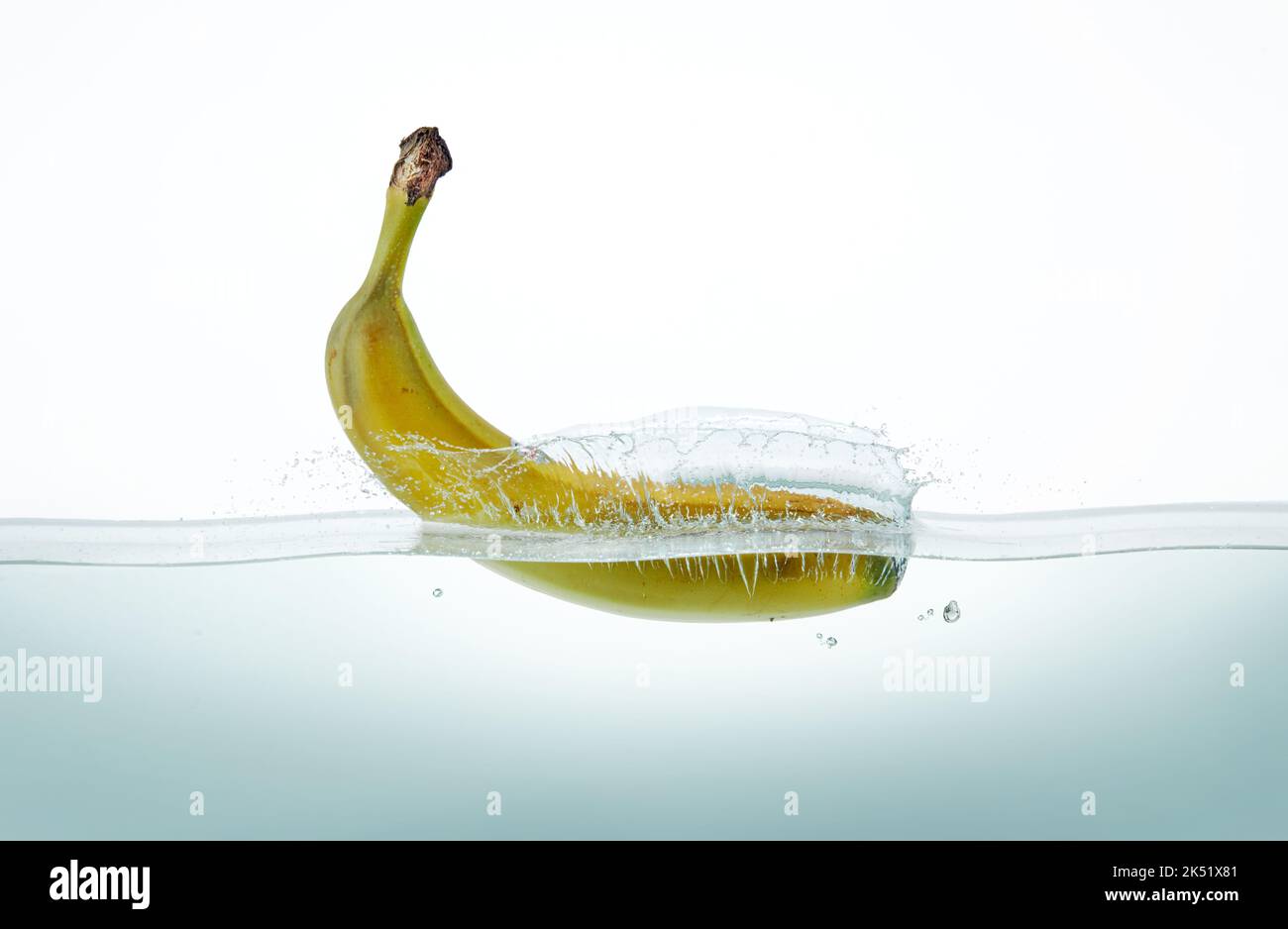 Banana spruzzata in acqua, vista da un lato su sfondo bianco. Foto Stock