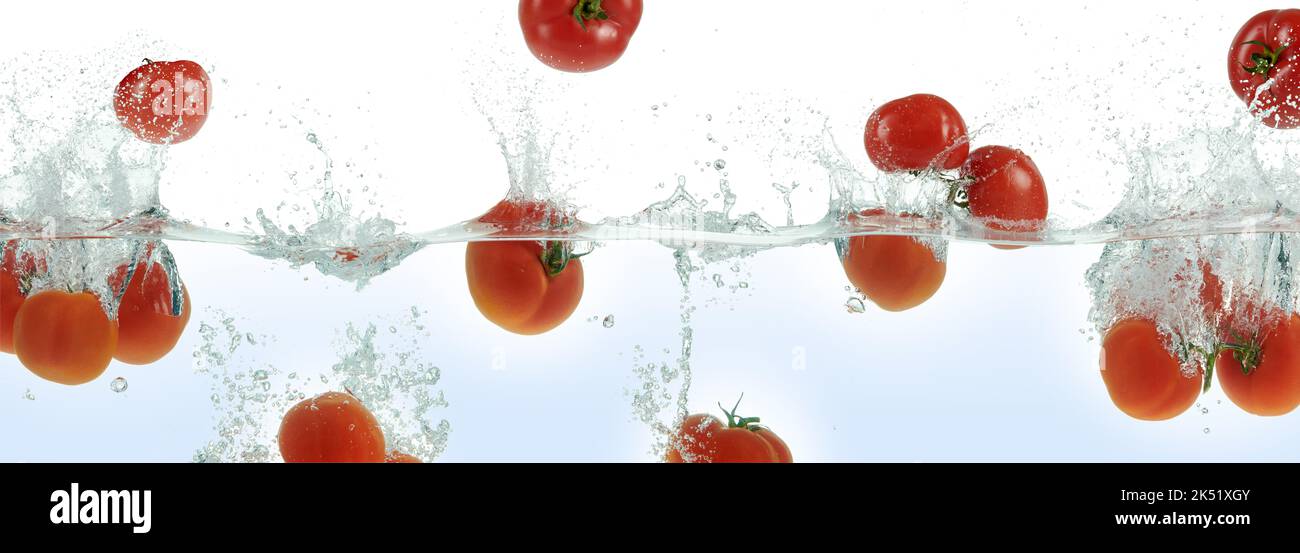 Molti pomodori spruzzano in acqua. Vista laterale panoramica su sfondo bianco. Foto Stock