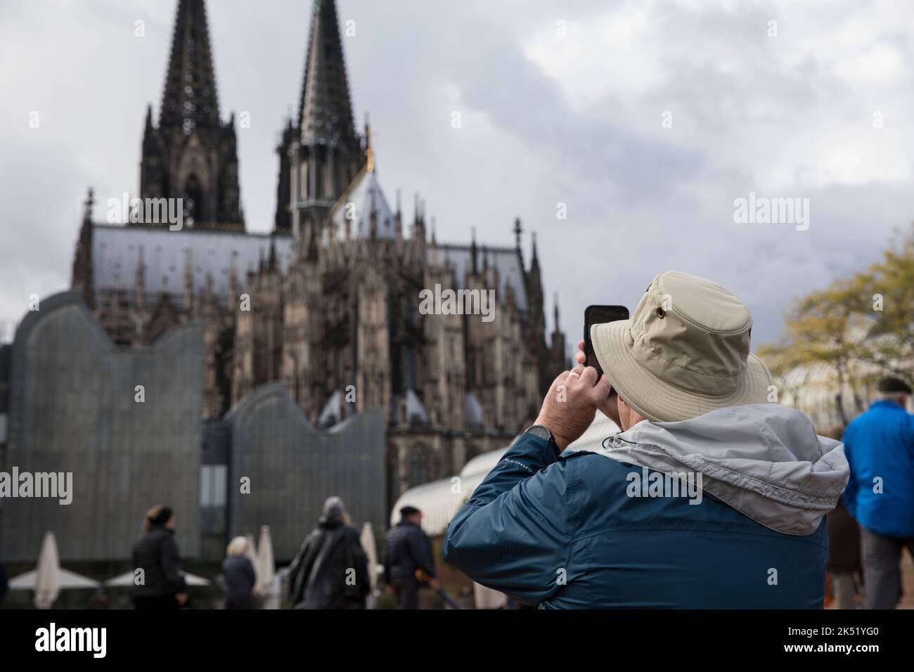 Turisti a Heinrich-Boell-Platz di fronte al Museo Ludwig e la cattedrale, l'uomo scatta foto della cattedrale di Colonia, Germania. Touristen auf dem Heinri Foto Stock