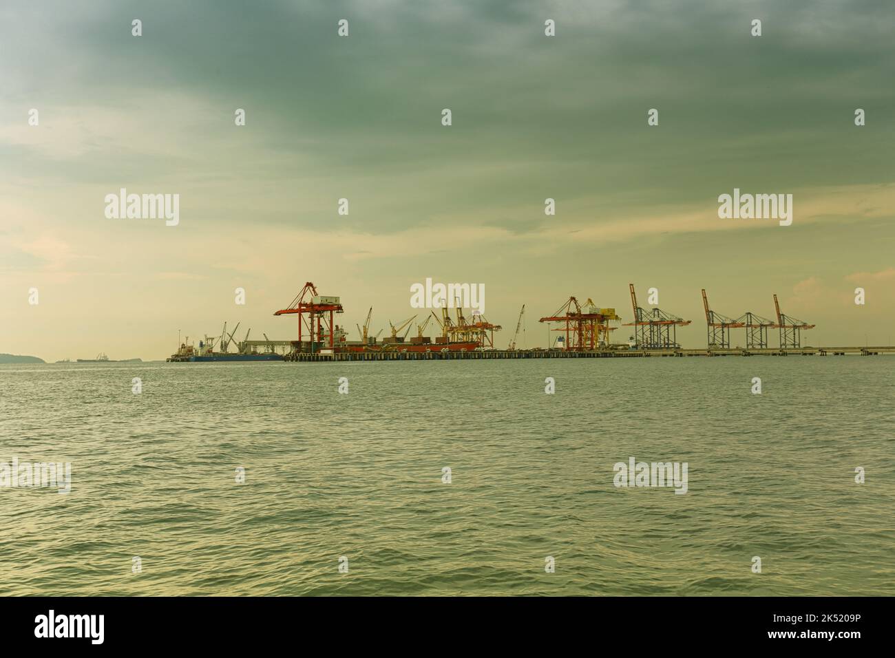 Vista di un porto in alto mare funzionante in colori vintage, carico e scarico di navi da carico. Foto Stock