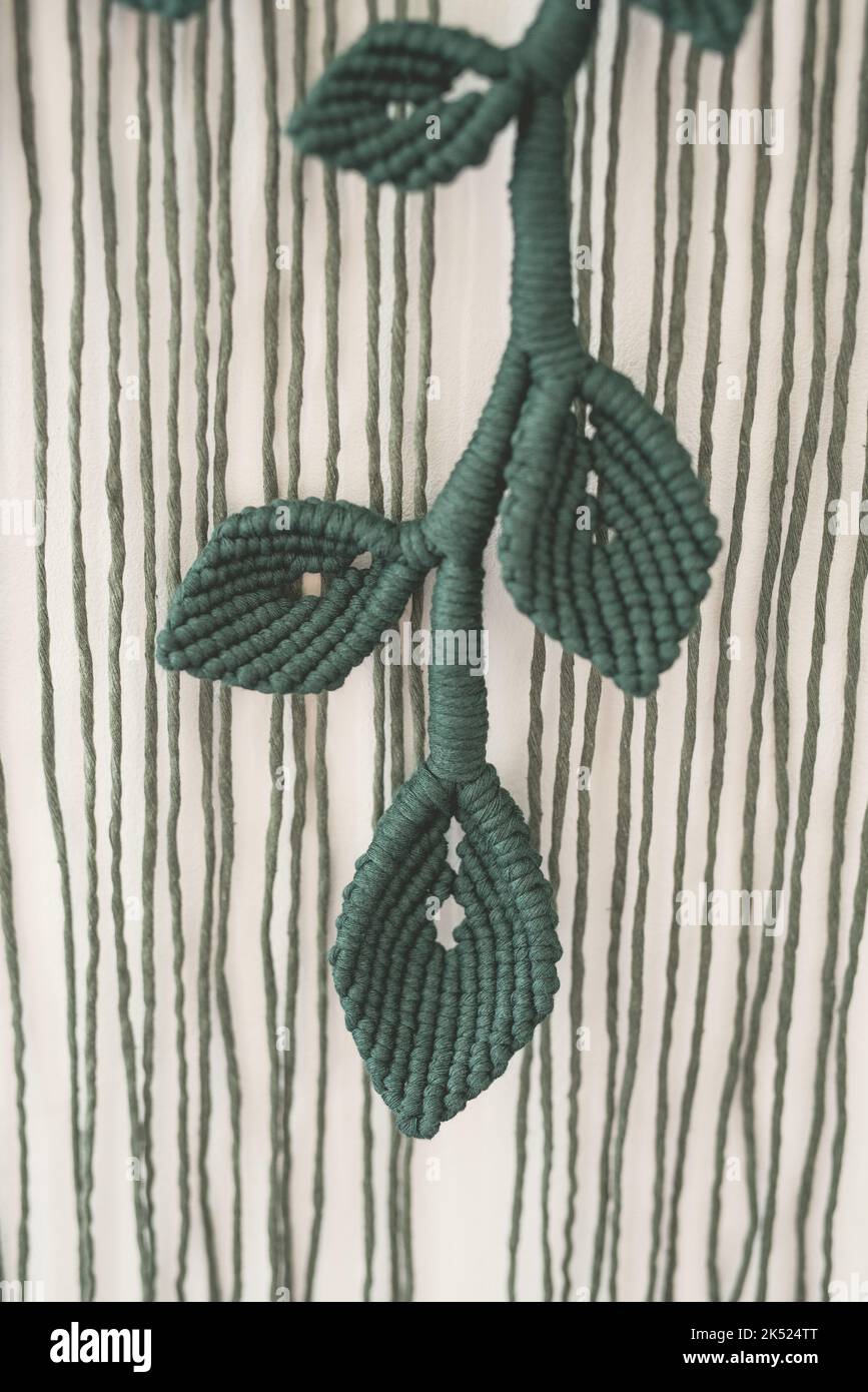 verde foglia ramo macrame artigianale parete artistica appeso fibra arte decorazione foglia simbolo legno bastone bianco sfondo interno pianta macramé deco Foto Stock