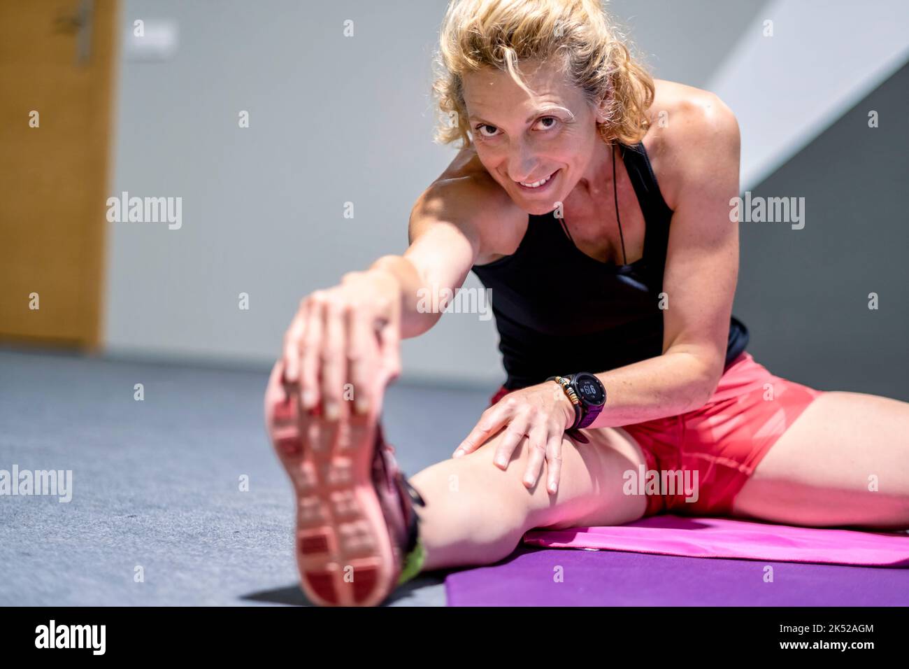 Vera giovane matura donna caucasica in un abbigliamento sportivo in palestra facendo stretching allenamento in palestra. Concetto di fitness. Foto Stock