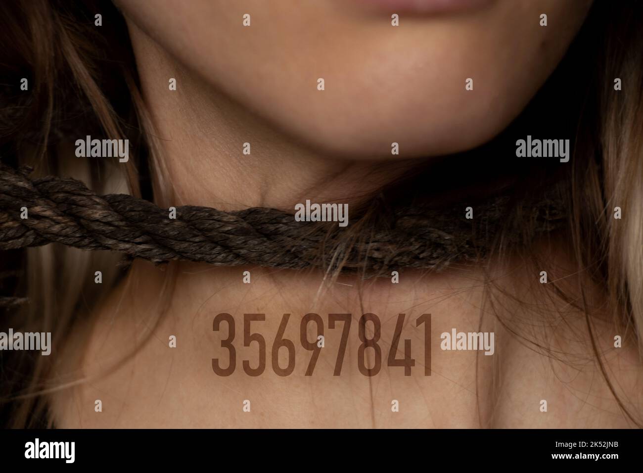 ragazza con una corda intorno al collo e un numero digitale sul petto, tratta di esseri umani, schiavitù, potere sulle persone, corda intorno al collo di una persona Foto Stock