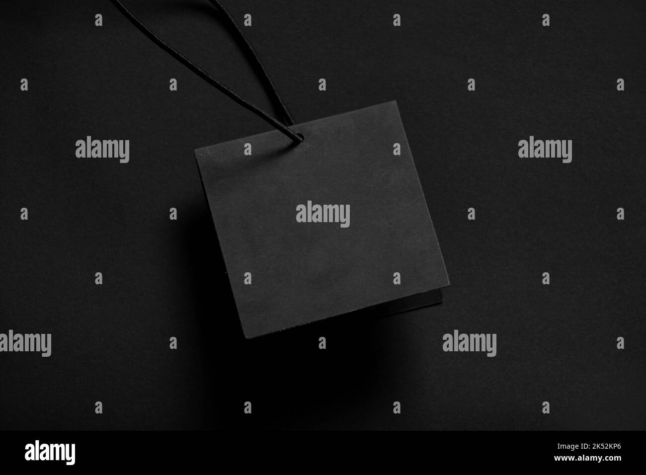 la scheda di carta nera si trova su uno sfondo nero, la carta bianca su una corda su uno sfondo isolato, il prezzo vuoto posto tag per il testo Foto Stock