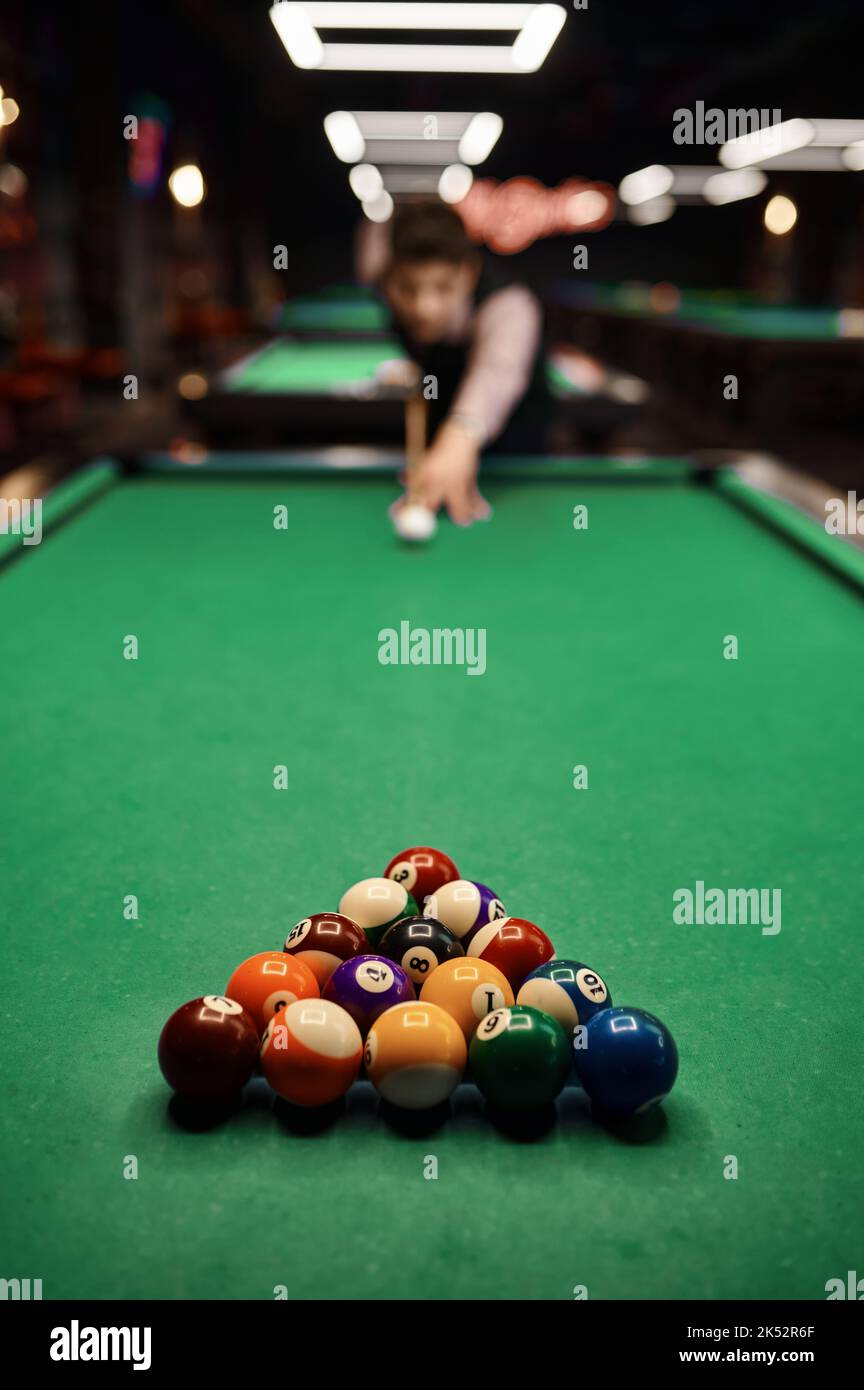 Giovane uomo che punta con stecca da biliardo Foto Stock