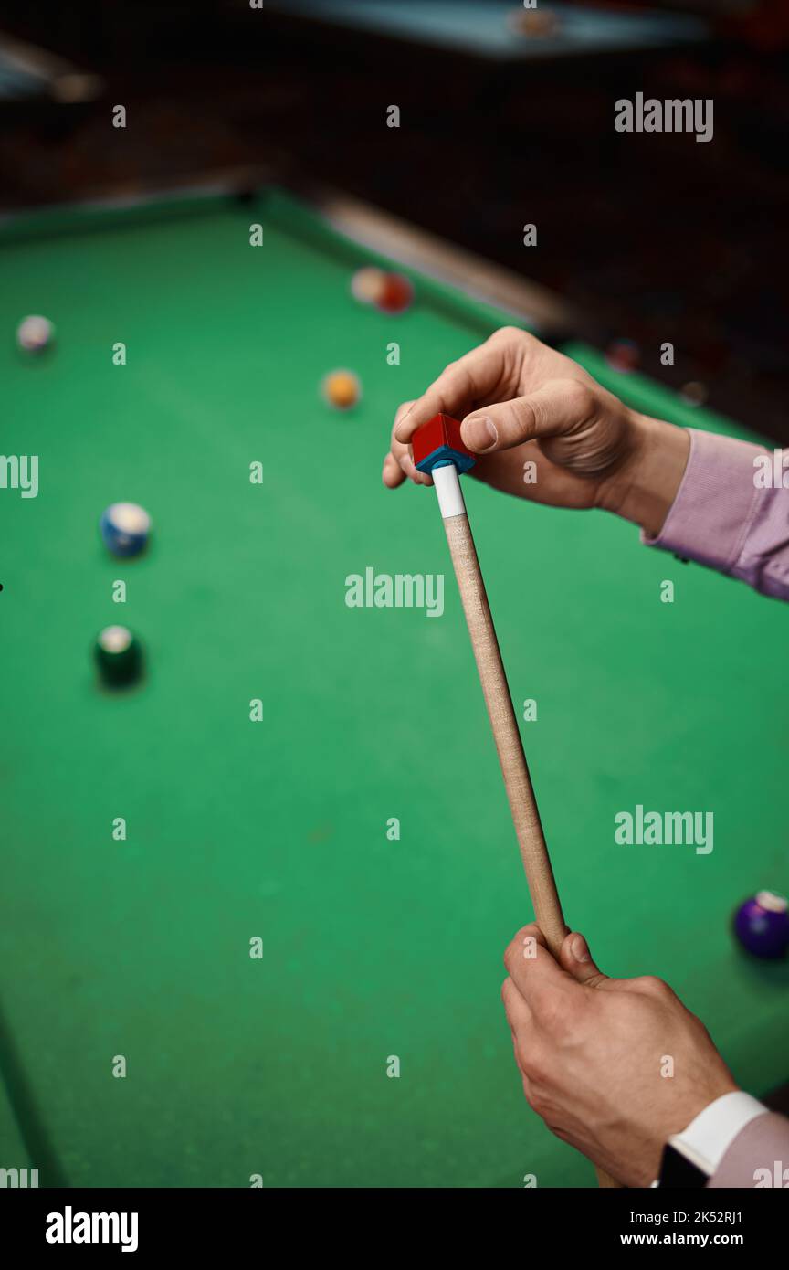 Closeup uomo giocatore biliardo rubbing cue Foto Stock