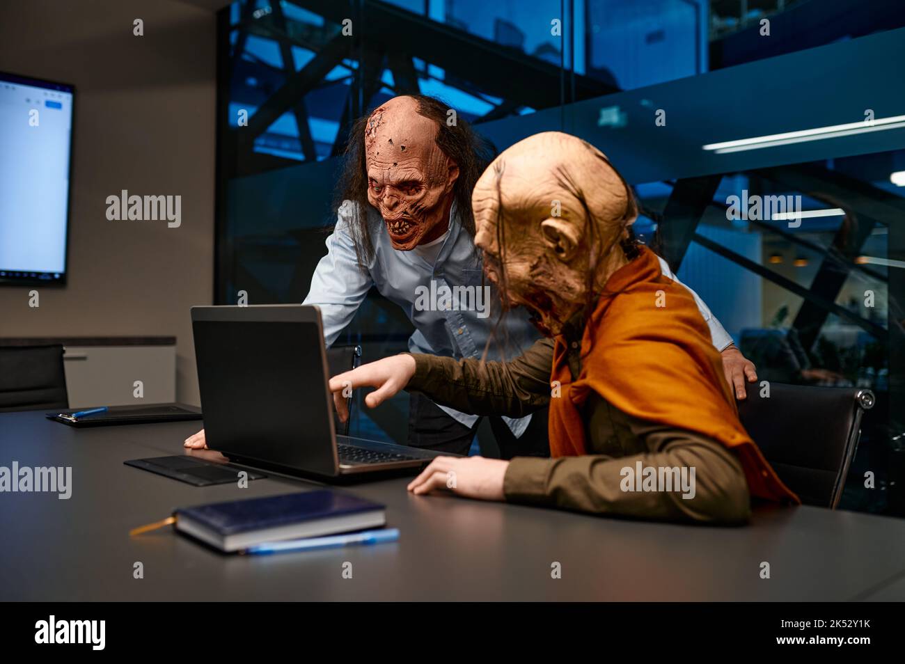 Dipendenti Zombie che cercano un notebook e parlano in ufficio notturno Foto Stock