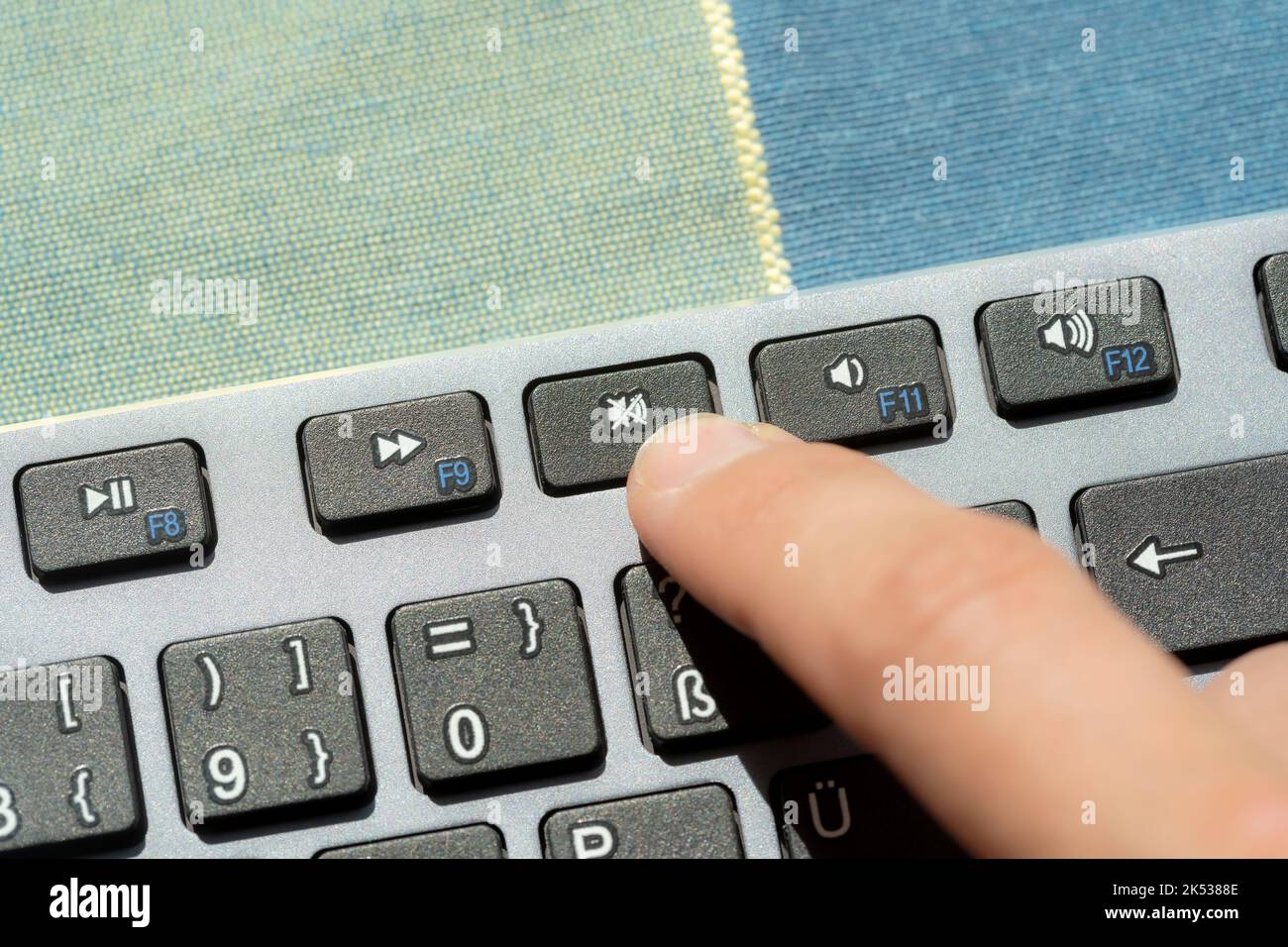 Anonimo uomo premendo il pulsante di esclusione microfono, suono off tasto su un computer moderno tastiera, mano, dito primo piano, dettaglio. Disattivazione audio, disattivazione audio, pace An Foto Stock