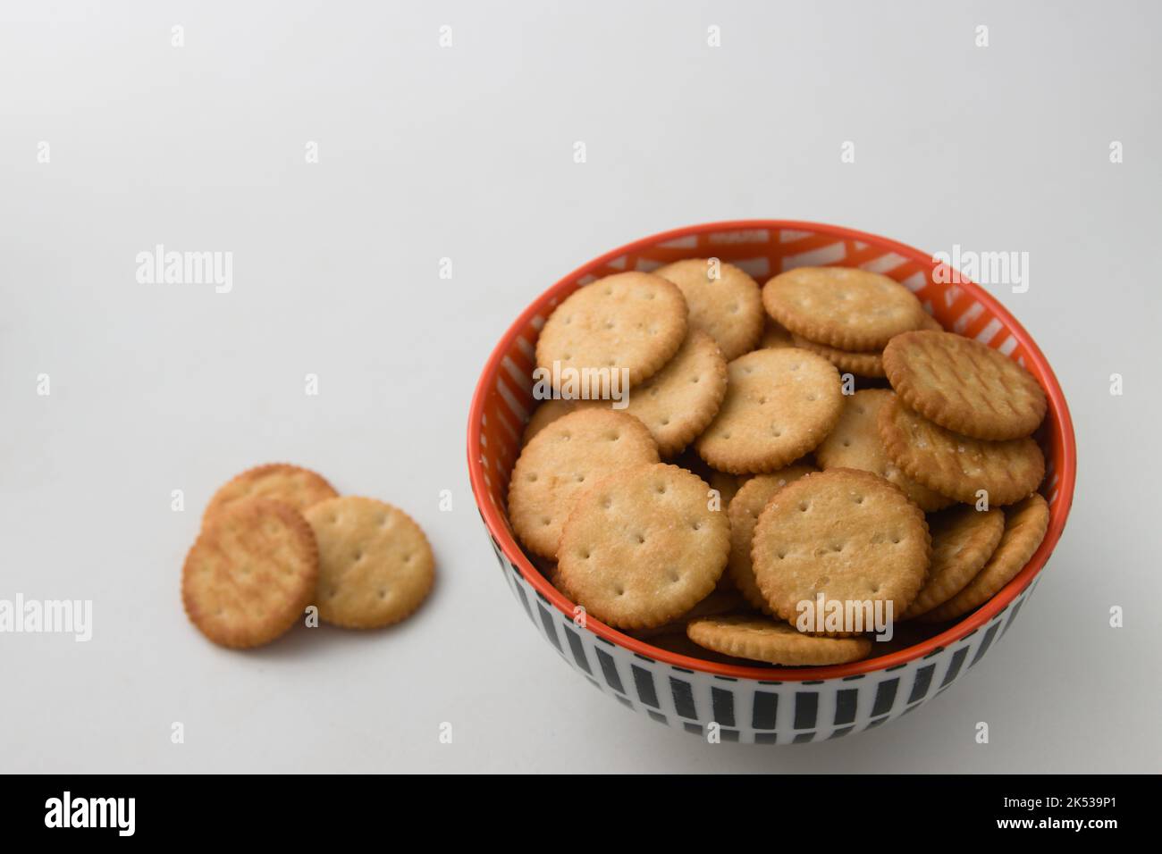 primo piano di una ciotola con cracker isolati accanto ad alcuni cracker sullo sfondo bianco, immagine con spazio di copia Foto Stock