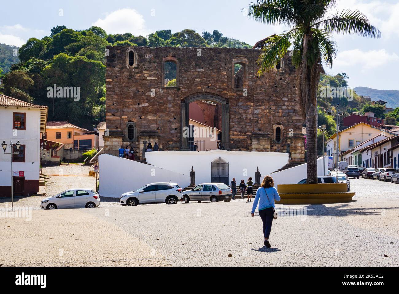 Donna che cammina a Delfim Moreira Praia di fronte a Igreja de Nossa Senhora do Rosário dos Pretos da barra a Sabará, Minas Gerais, Brasile. Foto Stock