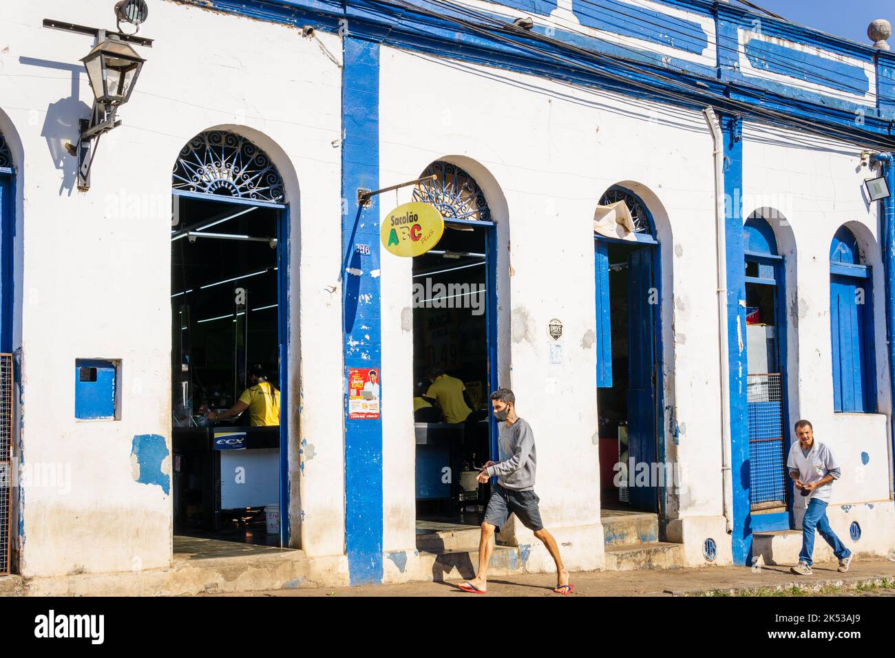 Due uomini che camminano di fronte a un negozio di alimentari a Sabará, Minas Gerais, Brasile. Foto Stock
