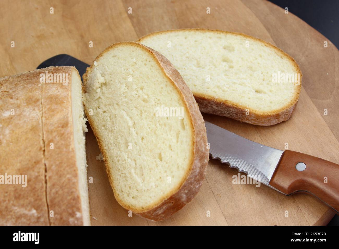 Coltello sta tagliando una pagnotta di pane a fette. Tagliare il pane fresco con un coltello Foto Stock