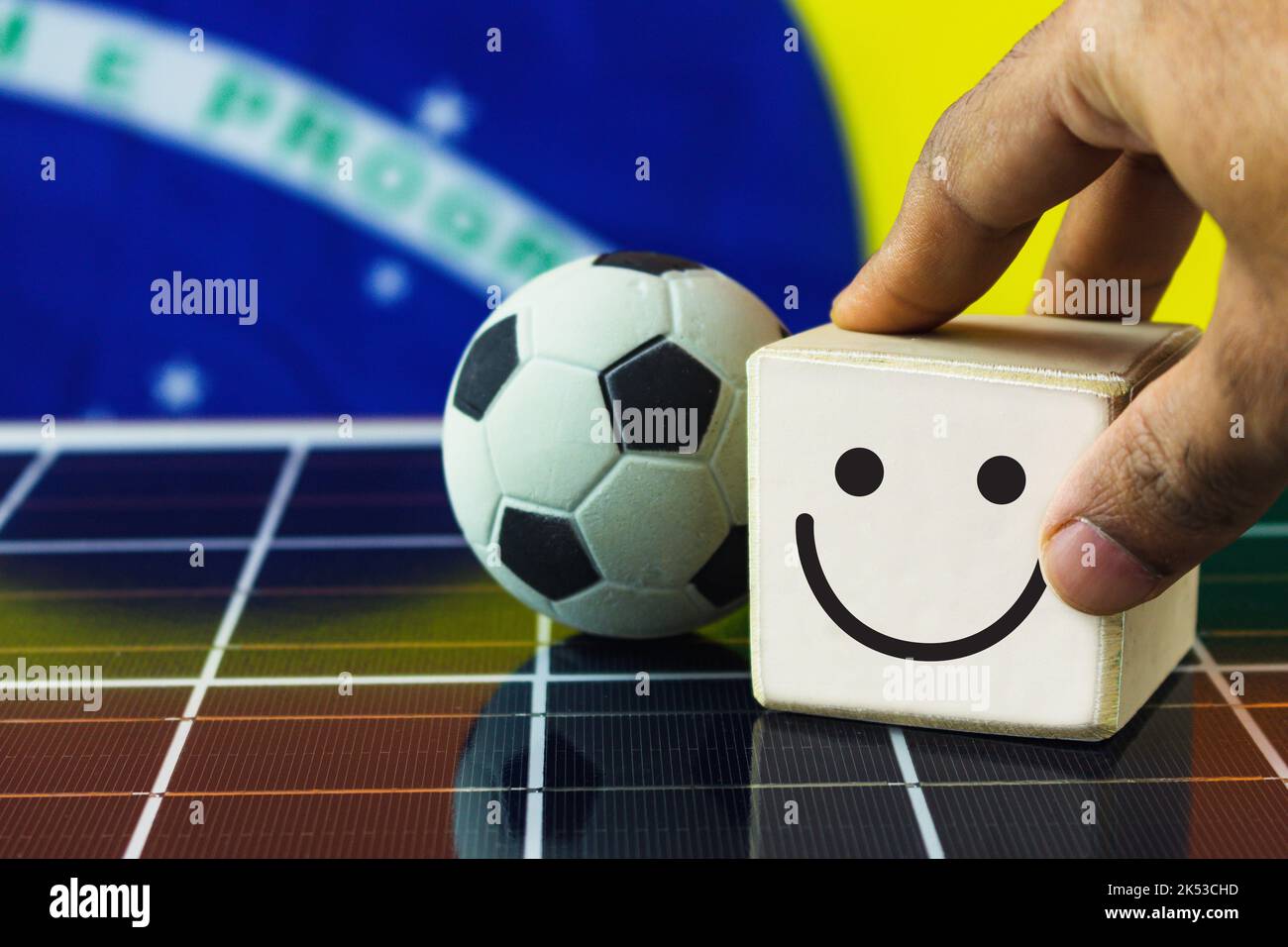 La mano mette i cubi di legno con il viso sorridente e il viso triste e Brazil Flag sul pannello solare fotovoltaico. Foto Stock