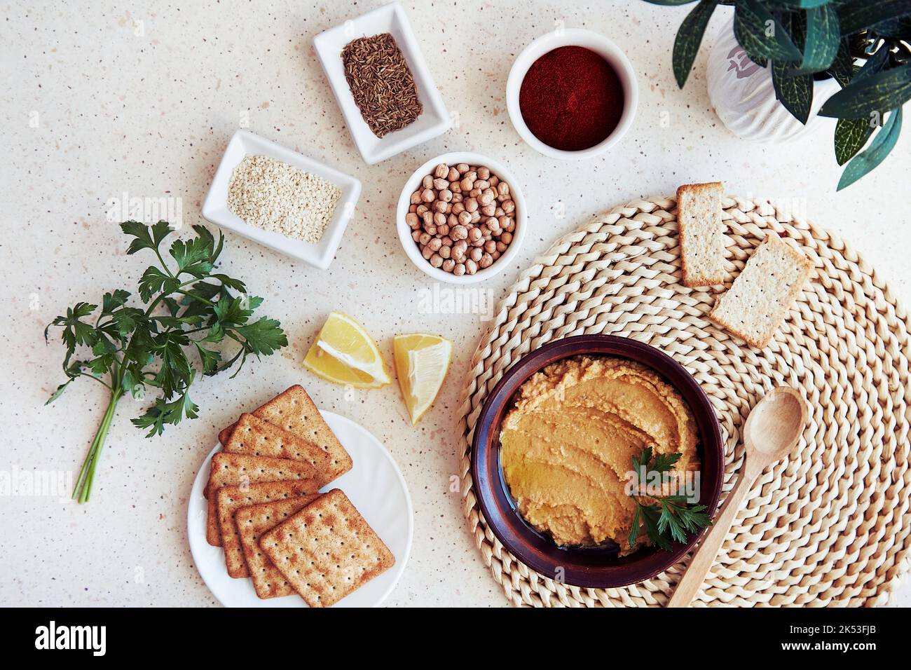 Antipasto vegetariano fatto in casa. Hummus tradizionale con biscotti di grano, prezzemolo, fettine di limone. Prezzemolo, paprika, semi di cumino romano, ceci, sesamo in Foto Stock