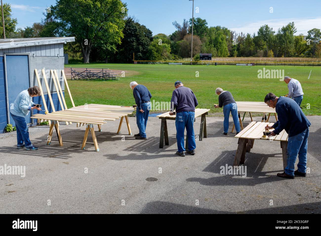 St. Johnsville, Montgomery County, New York: Volontari dipingono stecche di legno durante la riparazione della tribuna al campo di palla comunità. Foto Stock