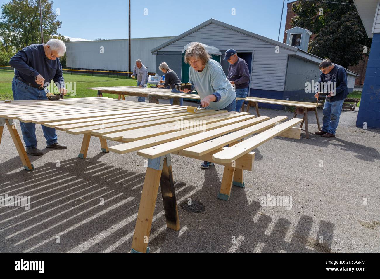St. Johnsville, Montgomery County, New York: Volontari dipingono stecche di legno durante la riparazione della tribuna al campo di palla comunità. Foto Stock