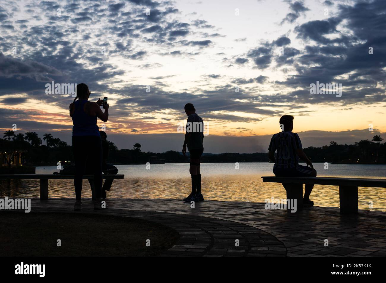 Persone che guardano un cielo crepuscolo e scattano una foto a Lagoa da Pampulha a Belo Horizonte, Brasile. Foto Stock