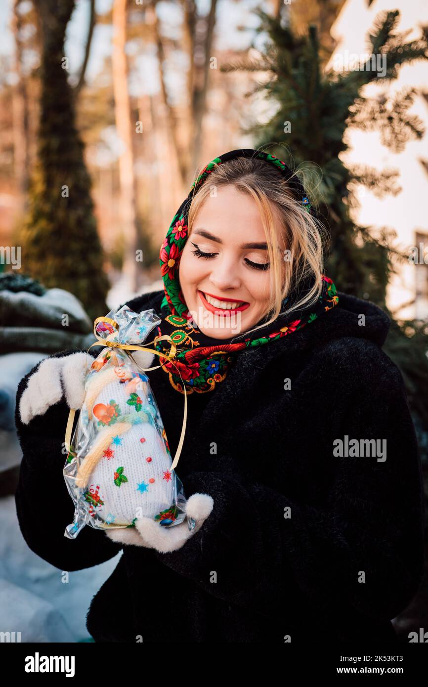 Bella giovane donna in un capo sciarpa nazionale Ucraina tiene un pupazzo di neve Foto Stock