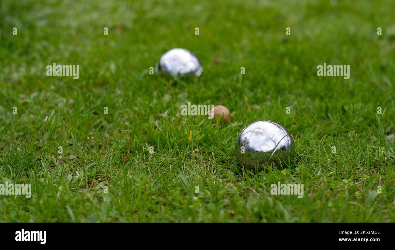 Primo piano di palle di bocce d'acciaio su un prato verde. Messa a fuoco selettiva. Palle di bocce in acciaio cromato giacciono sull'erba. Gioca nel tuo garde Foto Stock