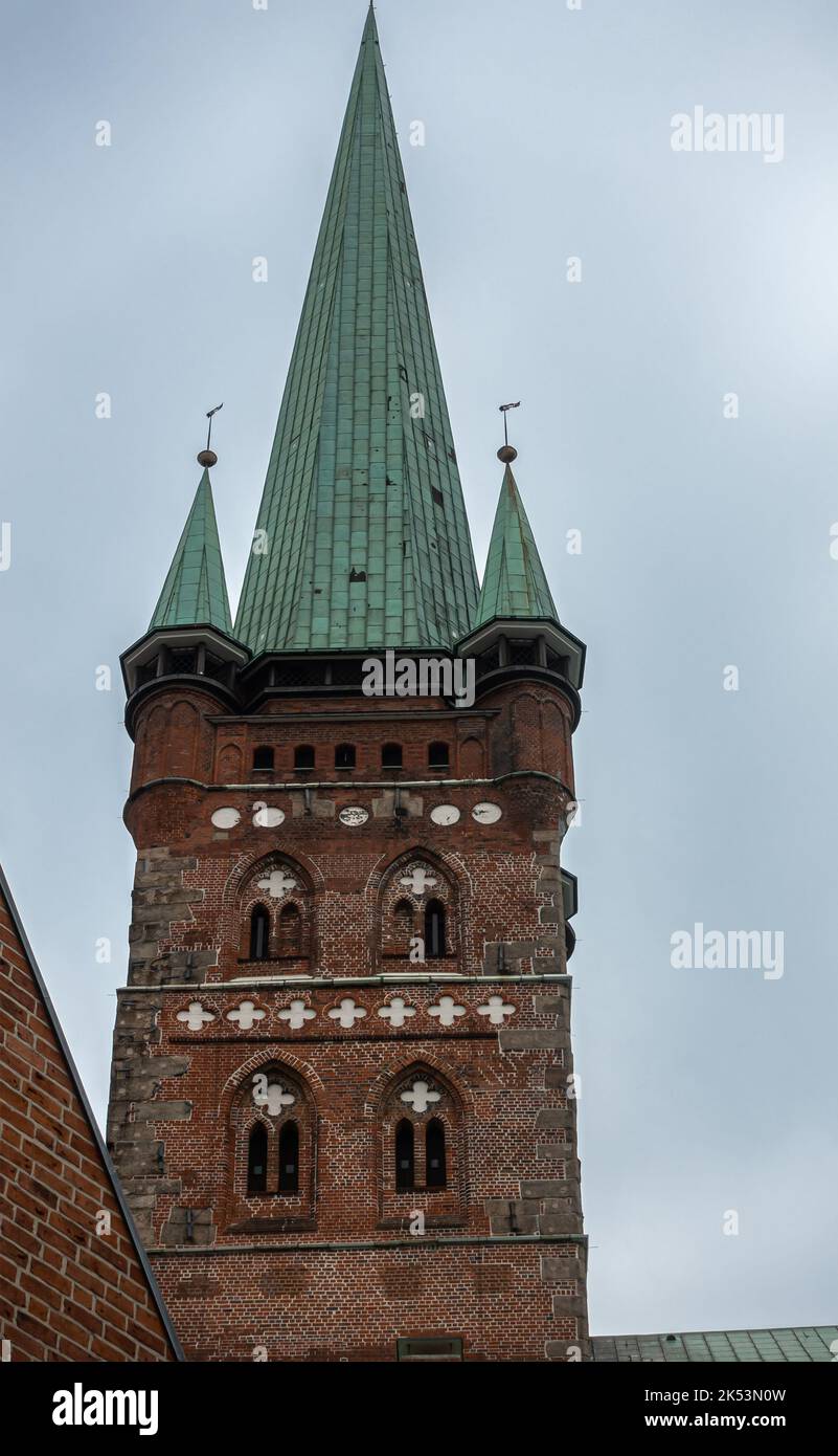 Germania, Lubecca - 13 luglio 2022: Primo piano, guglia verde sulla torre di mattoni marroni della Chiesa di San Petri, Pietro, contro il cielo azzurro Foto Stock