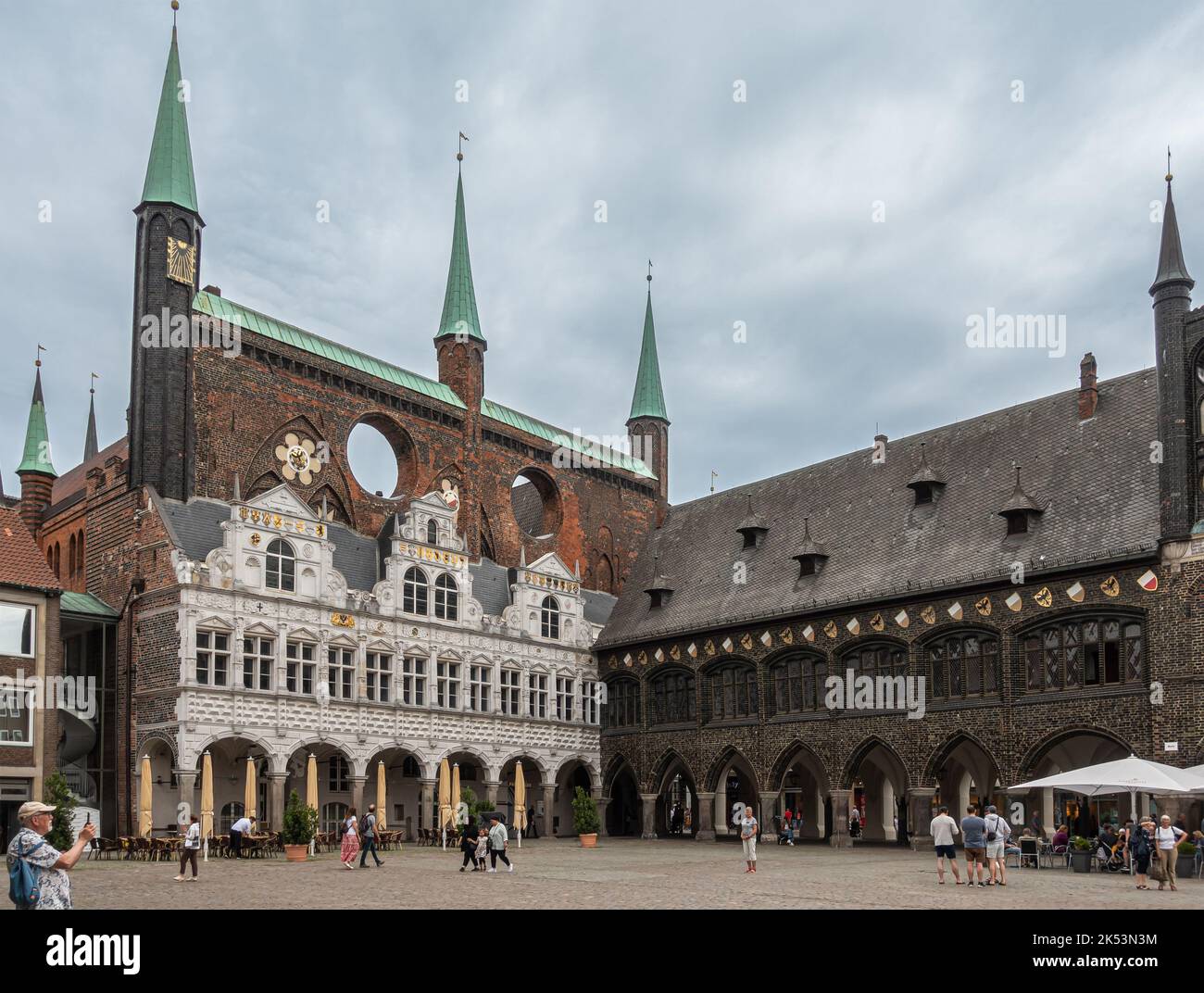 Germania, Lubecca - 13 luglio 2022: Hiistoric Rathaus o municipio in angolo NE di Marktplatz, piazza del mercato, sotto il paesaggio grigio nuvolato con persone a piedi a. Foto Stock