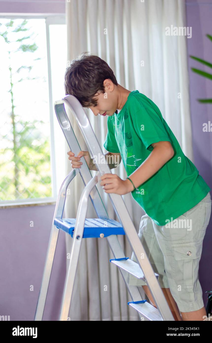 Ritratto di un bambino che sale su una scala in acciaio inossidabile. Abilità a casa. Salvador, Bahia, Brasile. Foto Stock