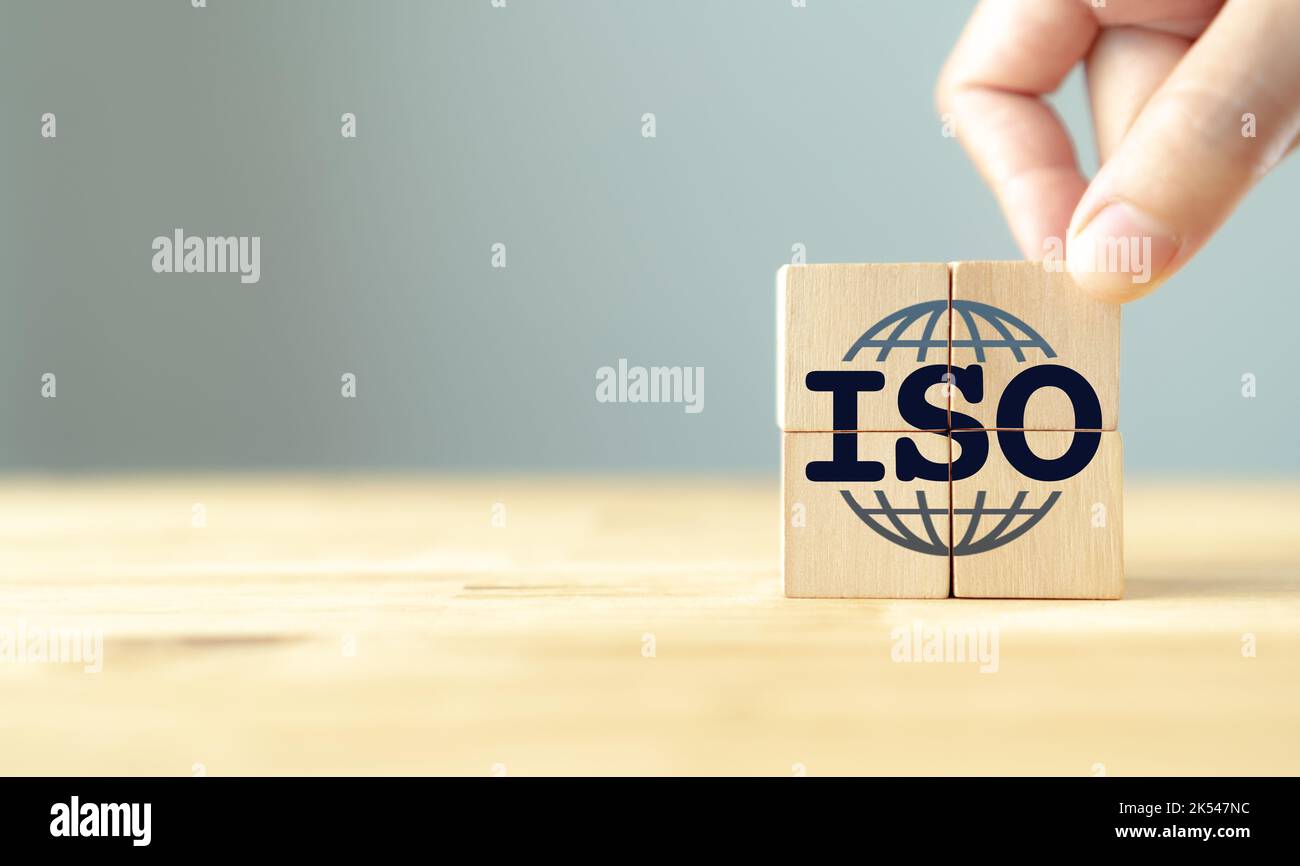 Concetto di certificazione del controllo di qualità degli standard ISO. Garanzia e garanzia di qualità. La mano mette i cubi di legno con le icone ISO e globo intelligente sul ba grigio Foto Stock