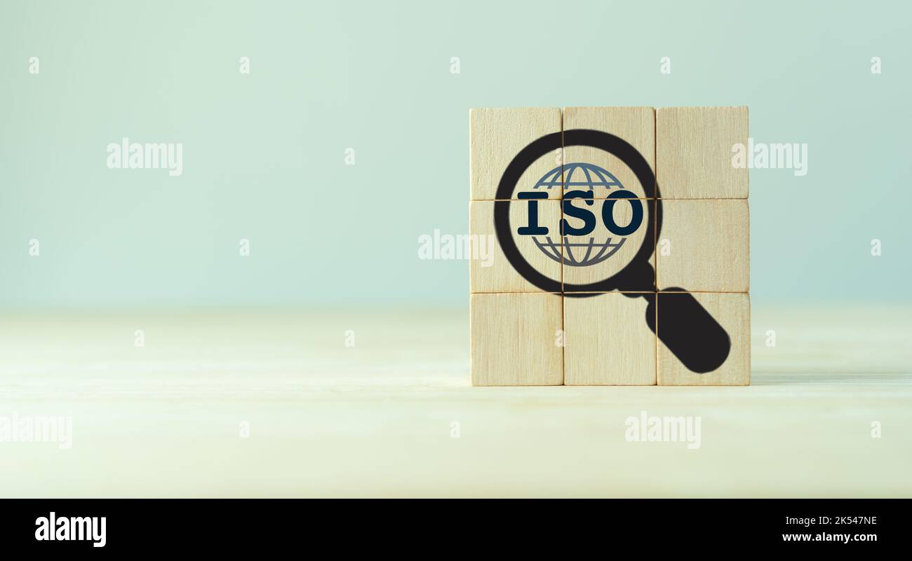 Concetto di certificazione del controllo di qualità degli standard ISO. Garanzia e garanzia di qualità. Cubi di legno con ISO, globo intelligente, icone lente di ingrandimento sul dorso grigio Foto Stock