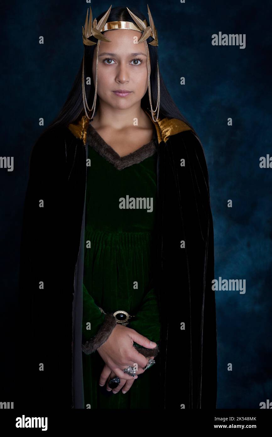 Una donna medievale o fantasy che indossa un vestito di velluto verde e un mantello marrone scuro Foto Stock