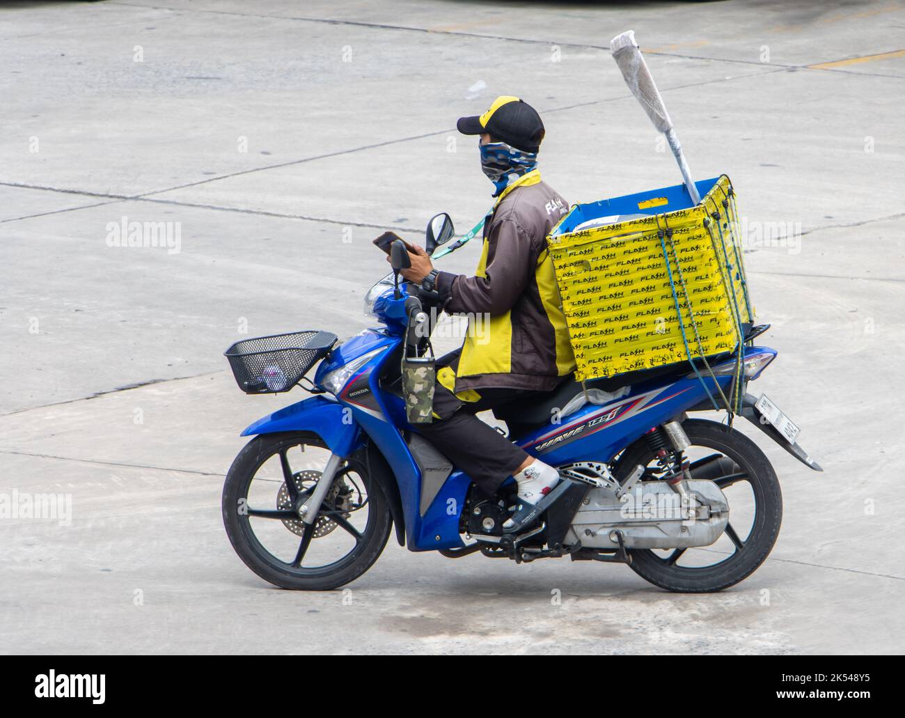 SAMUT PRAKAN, THAILANDIA, 04 2022 ottobre, Un lavoratore di consegna cavalca una moto con il telefono cellulare in mano Foto Stock