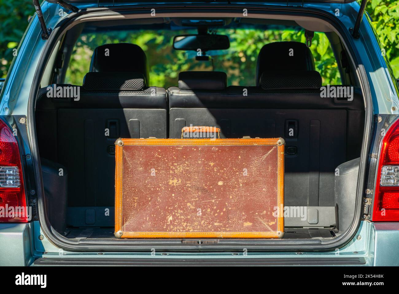 Vecchia valigia in pelle scabchiera nel bagagliaio di un'auto Foto Stock