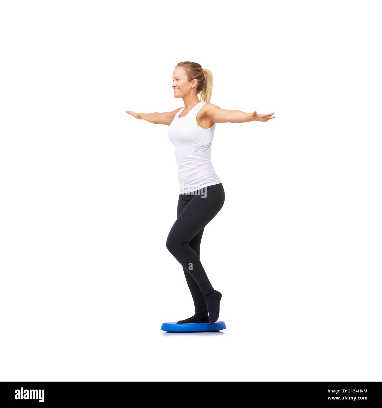 Mantenere il suo piede stabile. Full length studio shot di una donna attraente fare esercizi di equilibrio isolato su bianco. Foto Stock