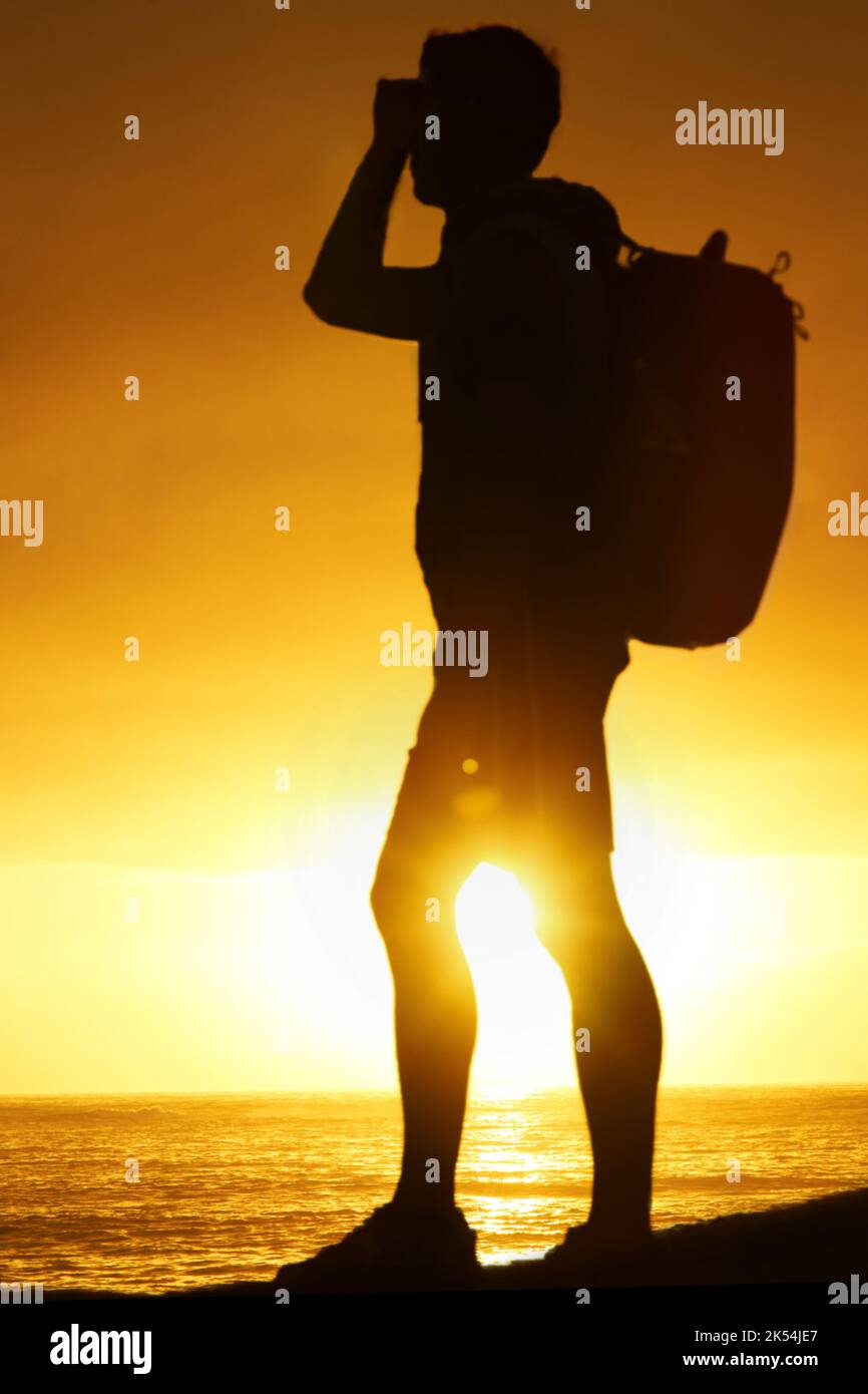 Goditi il tramonto sul mare. Silhouette di un escursionista in piedi e che guarda sopra l'oceano. Foto Stock