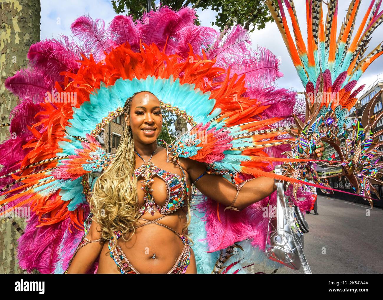 La ballerina Samba sorride in un costume scintillante e piume con Notting Hill Carnival, Londra, Regno Unito Foto Stock