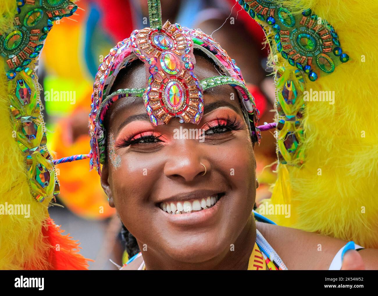 Donna afro-caraibica sorridente, faccia in primo piano, partecipante in costume al Notting Hill Carnival, Londra, Inghilterra Foto Stock