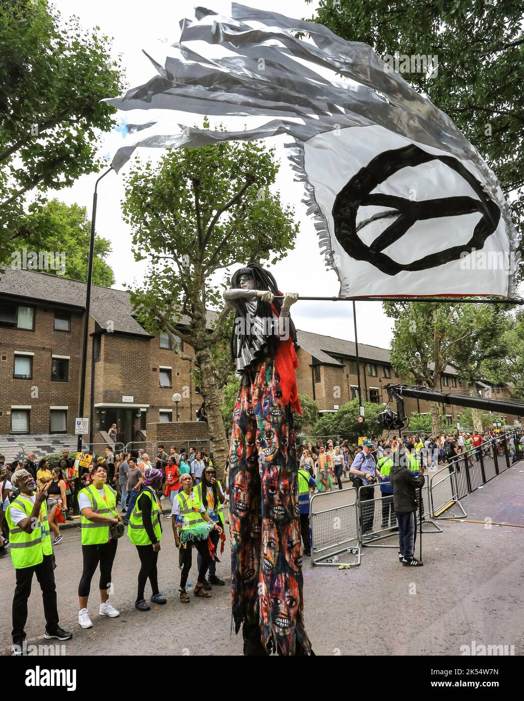 Camminatore con bandiera con segno di pace a Notting Hill Carnival, Londra, Inghilterra, Regno Unito Foto Stock