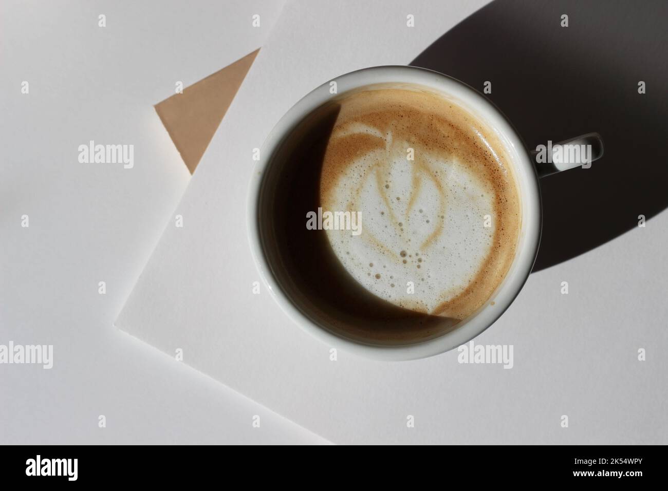 Cappuccino fresco con latte Art su fogli di carta bianca, carte. Design a piano di lavoro minimo. Pausa caffè business. Foto Stock