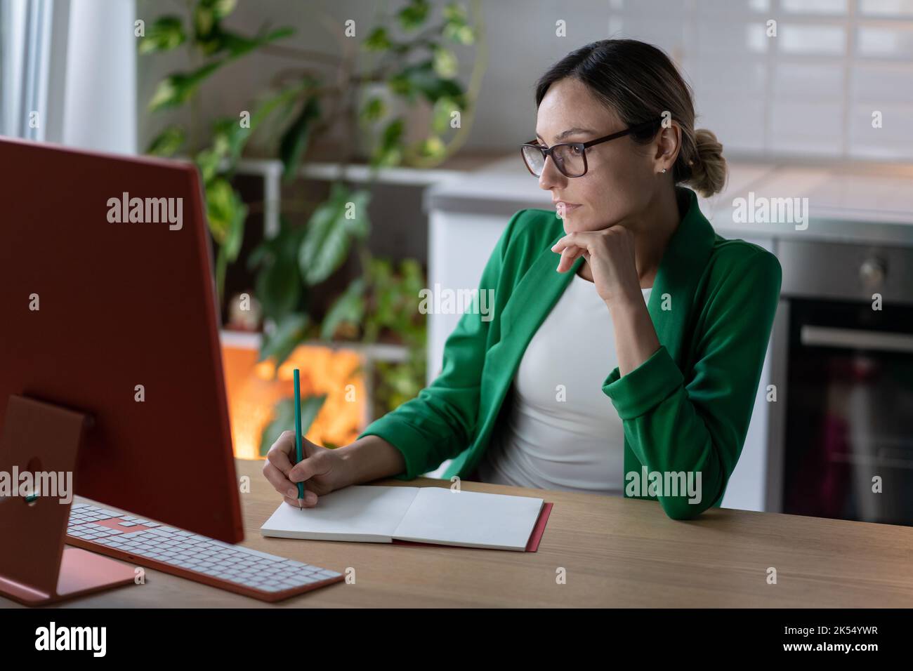 Donna freelance fa il piano per il progetto di business, lavorando al computer in un accogliente ufficio domestico con impianto Foto Stock