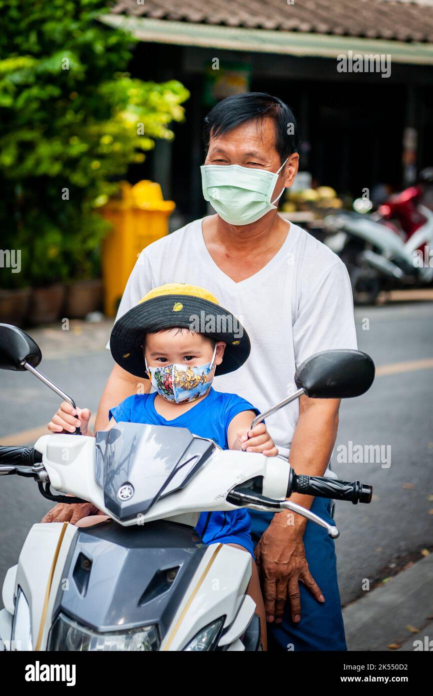 Un piccolo ragazzo tailandese fa un giro sulla parte anteriore di una moto a Bangkok Thailandia. Foto Stock