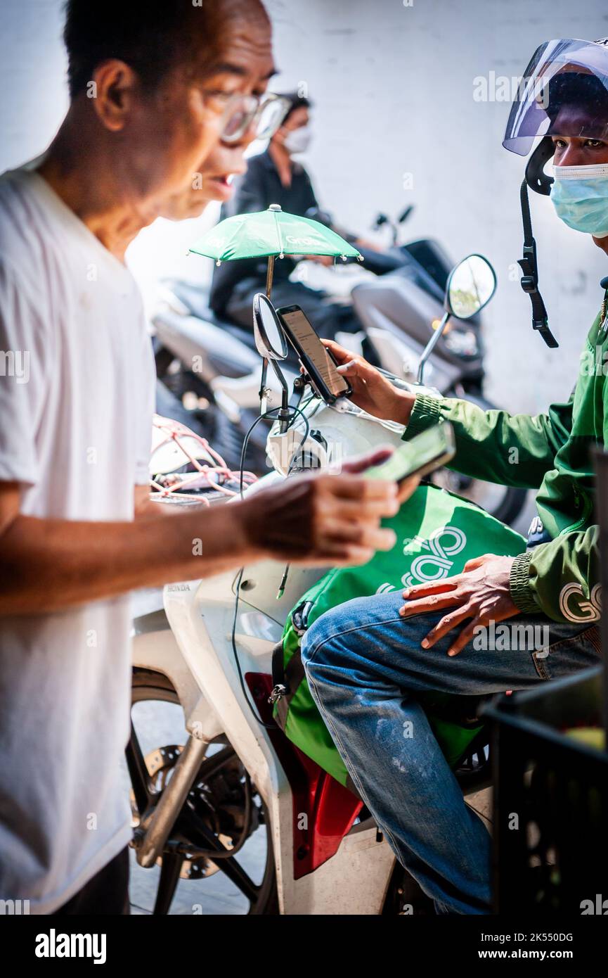 Un corriere della bici del grab arriva per ritirare un pacco in Thailandia di Bangkok. Foto Stock