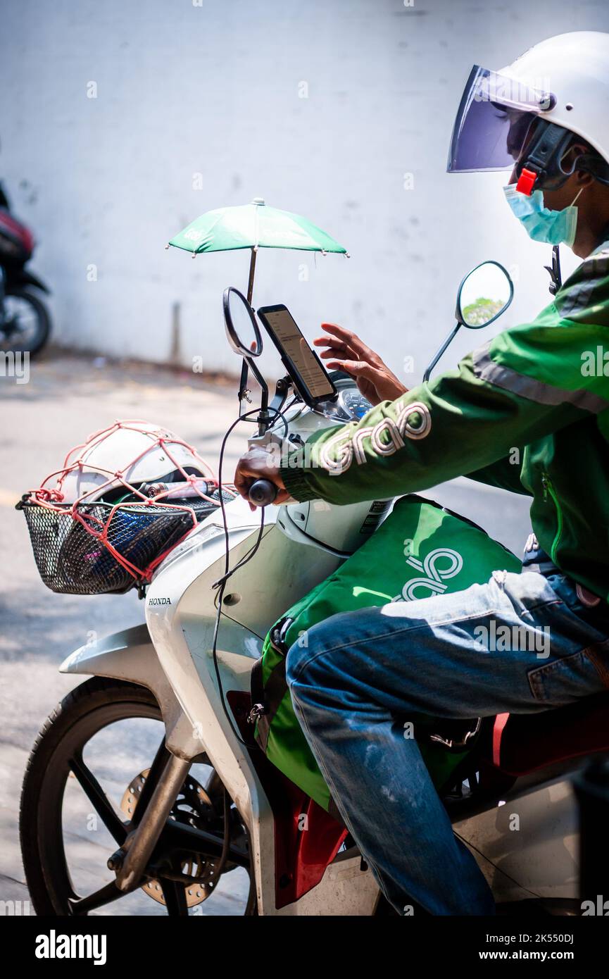 Un corriere della bici del grab arriva per ritirare un pacco in Thailandia di Bangkok. Foto Stock