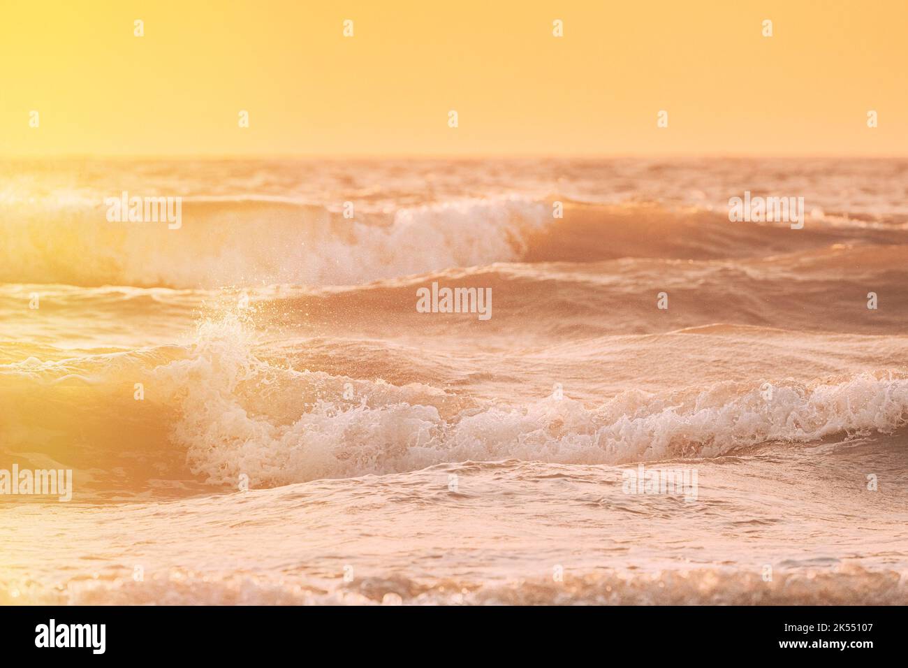 Riplpe mare oceano superficie con piccole onde. Primo piano della schiuma marina dall'onda di rottura. Tramonto naturale cielo colori caldi. Bella natura mare Foto Stock