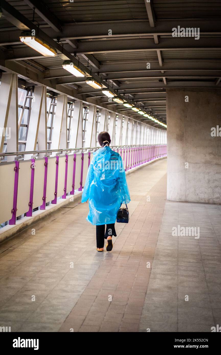 Una giovane signora tailandese fa la sua strada lungo una camminata in cielo verso un treno sopraelevato BTS a Bangkok, Thailandia. Foto Stock