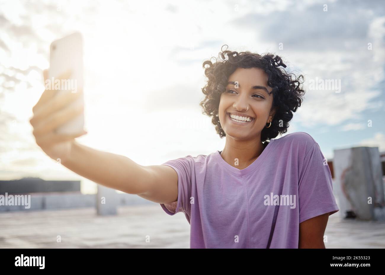 Telefono, selfie e social media con una donna che scatta una fotografia all'esterno della città con un cielo fiabato in India. Felice, sorridere e fotografare con un Foto Stock