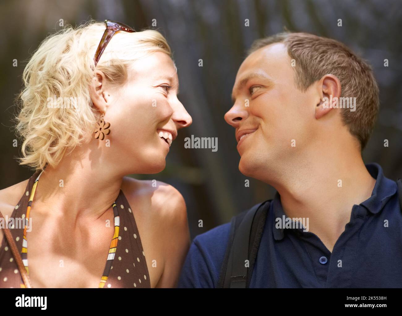 Non riesco proprio ad avere abbastanza di te...una coppia seduta fuori e sorridente l'una verso l'altra. Foto Stock