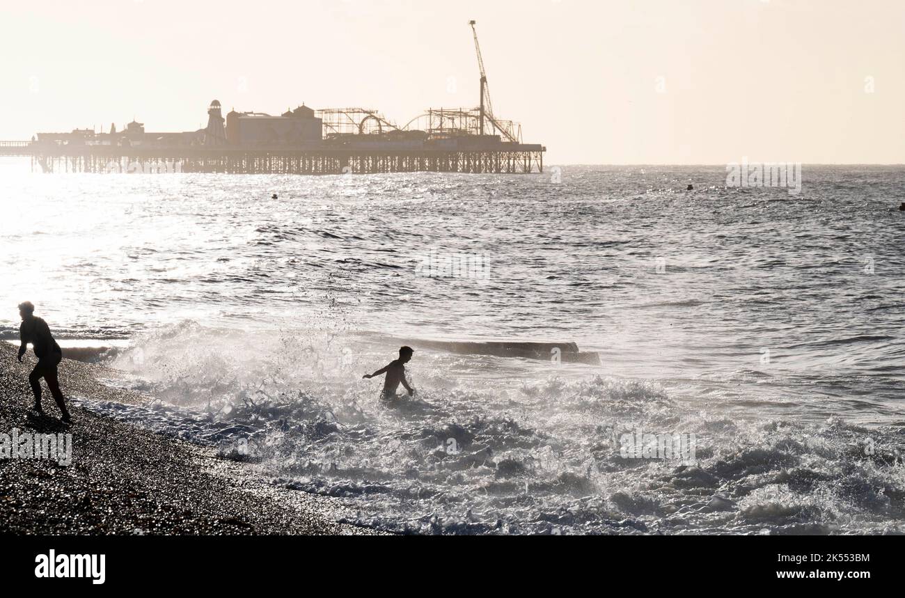 Brighton UK 6th ottobre 2022 - i nuotatori godono di una bella mattina soleggiata ma fredda a Brighton come le onde rotolare sulla spiaggia : Credit Simon Dack / Alamy Live News Foto Stock